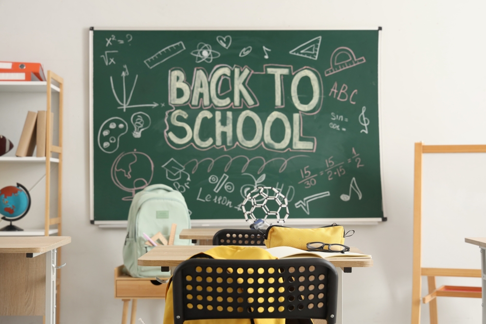 School,Desk,With,Backpack,And,Notebook,In,Light,Classroom